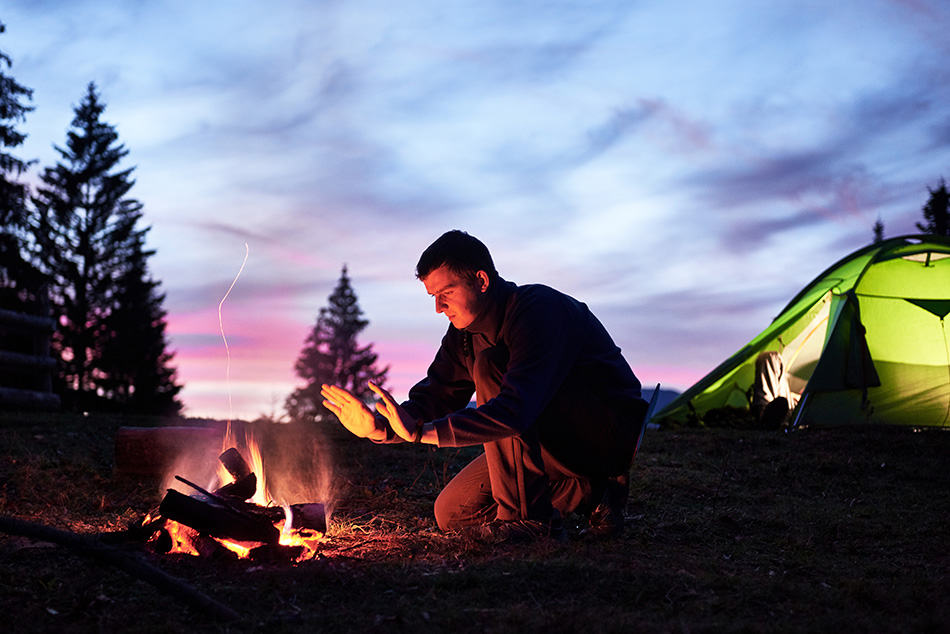 Man camping alone beside campfire