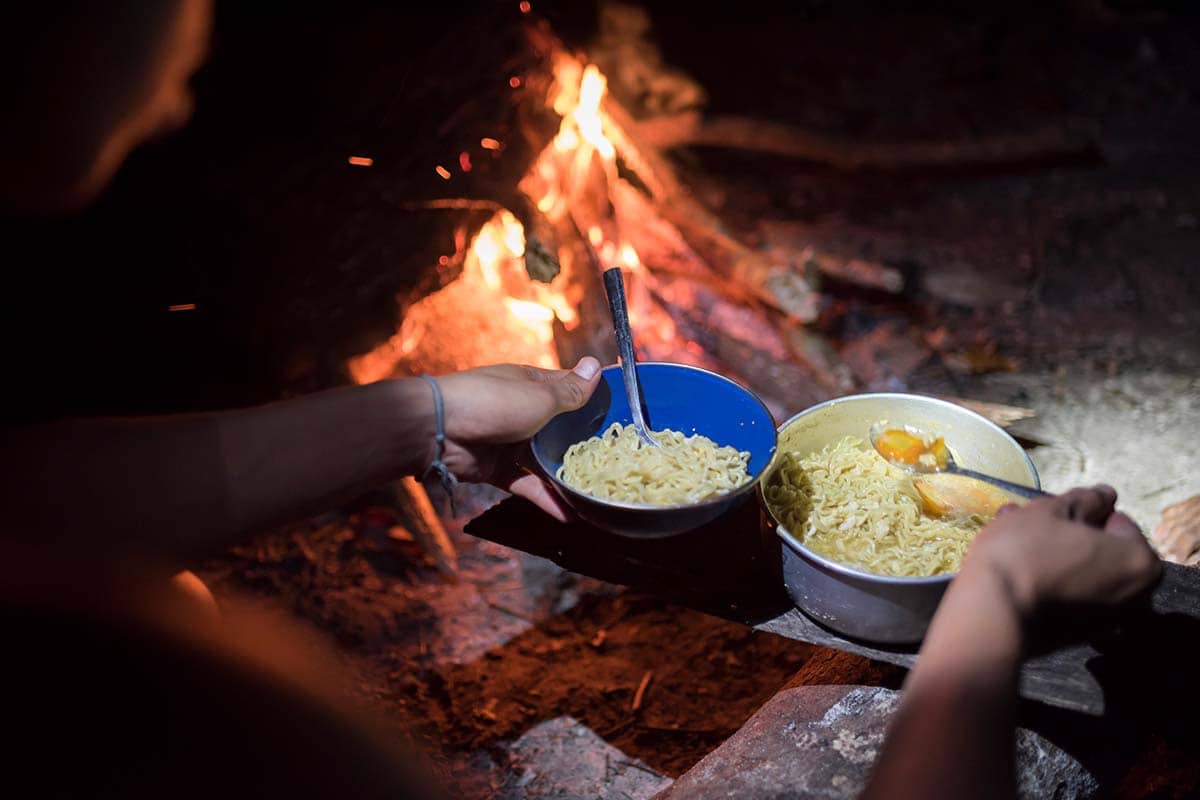 Cooking noodles over campfire